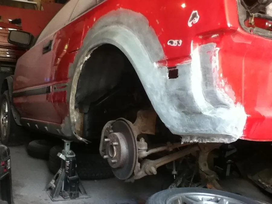 Fiberglass repair work on red vehicle quarter panel