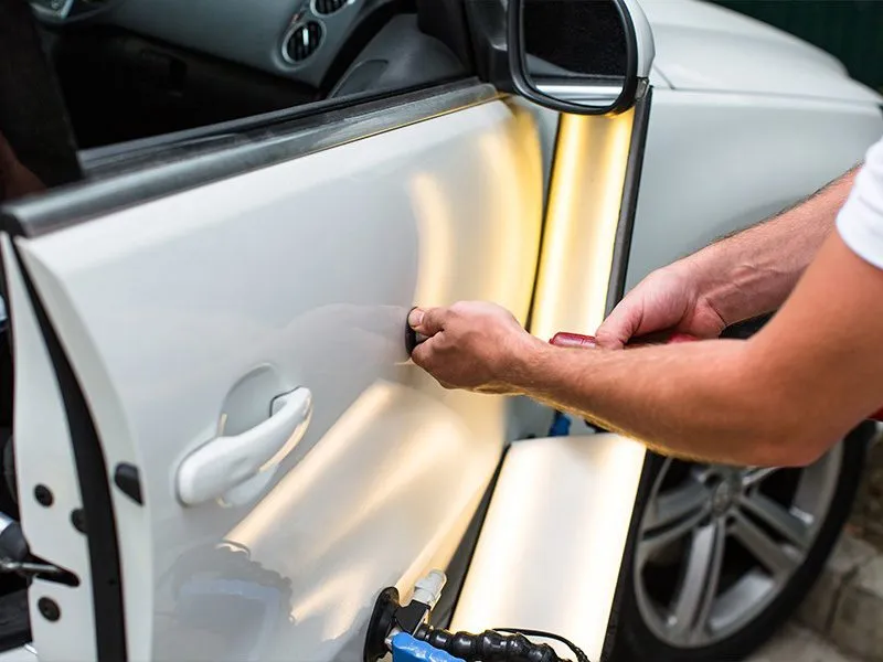 Paintless dent repair on white vehicle door